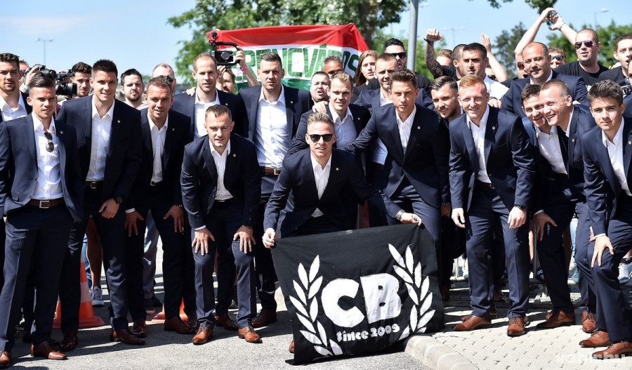 A magyar labdarúgó-válogatott tagjai indulás előtt a szurkolókkal, középen Dzsudzsák Balázs csapatkapitány a drukkeretől kapott zászlóval, a Liszt Ferenc Nemzetközi Repülőtér I-es terminálja előtt 2016. június 7-én. Az Eb-re 44 év után kijutott válogatott június 14-én Ausztriával játszik Bordeaux-ban, majd négy nappal később Marseille-ben Izland, végül június 22-én, Lyonban Portugália lesz az ellenfele. MTI Fotó: Illyés Tibor