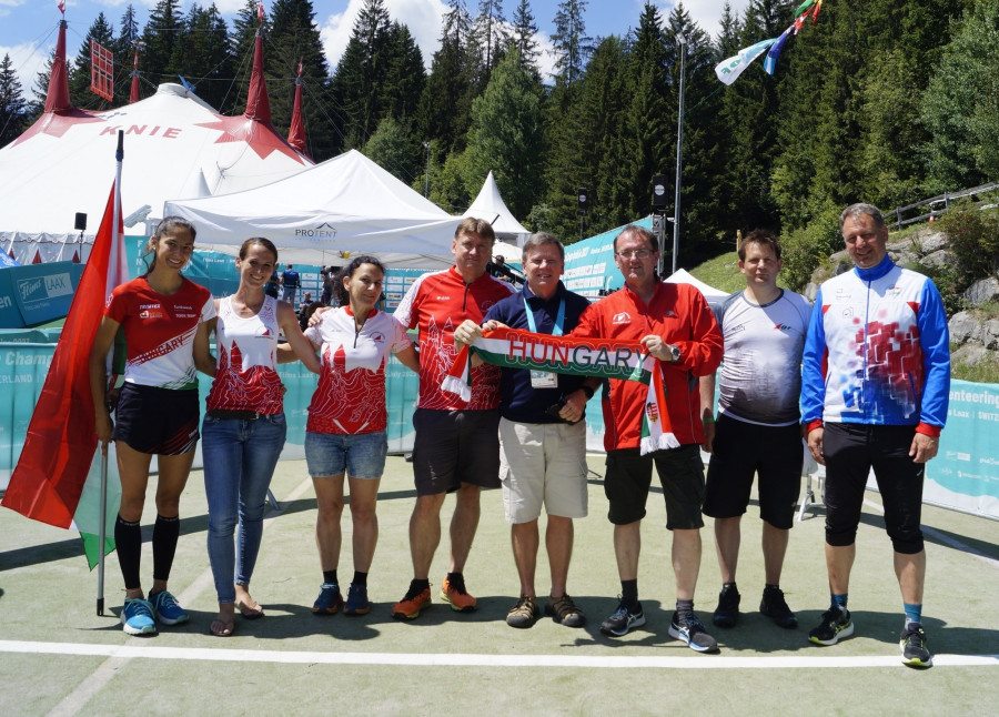 Leho Haldna (IOF elnök) a döntés után a Svájcban gratulál Varsányi Attilának és a magyar küldöttségnek. A képen: Mérő Dominika, Varsány Kinga, Wengrin Ágnes, Faggyas László, Leho Haldna, Varsányi Attila, Less Áron, Molnár Péter.